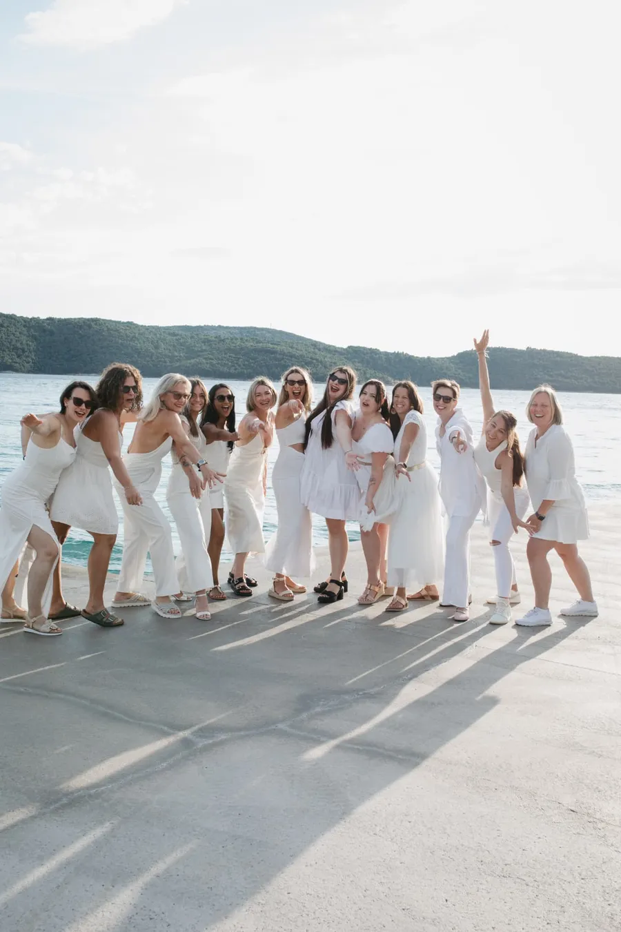 Gruppenfoto aller Teilnehmerinnen in weißen Outfits am Meer